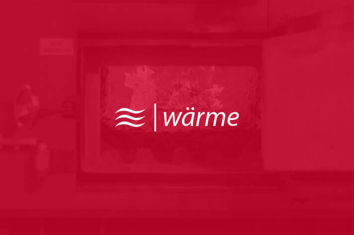 Schriftzug Wärme steht vor einem Blockheizkraftwerk mit offenen Ofen